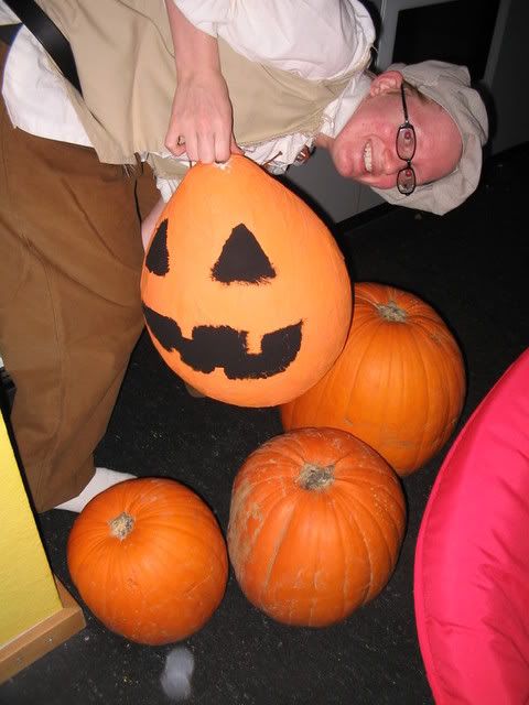 Joslyn dressed as a peasant next to the carving pumpkins holding a pinata
