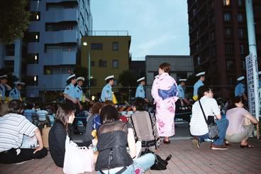 Noia en yukata i mòbil i policia de fons